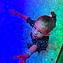 child, girl, ball_pit, reaching, colorful_lighting, play, curious, young, portrait, indoor, fun, entertainment, toy, happy, person, face, hair_tie, wristband, clothing, expression