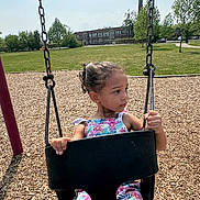 Legacy joined the competition — help win amazing prizes! child, girl, swing, playground, outdoor, summer, park, chains, woodchips, grass, trees, building, casual_clothing, daylight, curly_hair, expression, seat, holding, young, nature
