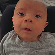 Ryder is registered to the contest to win money with this photo: baby, infant, face, eyes, mouth, clothing, shirt, gray, blanket, cute, child, portrait, indoors, cozy, expression, young, person, closeup, skin, head