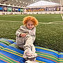 Madilynn is registered to the contest to win money with this photo: child, curly_hair, gray_tracksuit, sneakers, indoor_soccer_field, striped_mat, green_turf, sports, playing, relaxing, people, background, banner, lighting, athletic, casual, floor, person, activity, team