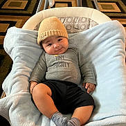 Gael joined the competition — help win amazing prizes! baby, infant, child, hat, knit_hat, blanket, baby_rocker, smile, happy, clothing, socks, indoor, carpet, patterned_carpet, cozy, cute, relaxed, portrait, person, soft_fabric