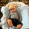 baby, infant, child, hat, knit_hat, blanket, baby_rocker, smile, happy, clothing, socks, indoor, carpet, patterned_carpet, cozy, cute, relaxed, portrait, person, soft_fabric