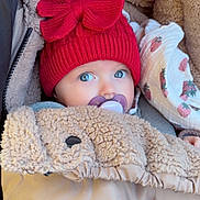 Elya participe au concours pour gagner de l'argent avec cette photo : baby, pacifier, red_hat, blanket, fleece, stroller, infant, cozy, cute, warm_clothing, blue_eyes, child, portrait, wrapped, winter_wear, headwear, closeup, sitting, soft_texture, outdoor