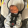 newborn, baby, infant, child, car_seat, harness, safety, seated, portrait, face, eyes_open, striped_clothing, onesie, indoors, vehicle, infant_carrier, cushioned_seat, looking_away, photograph, safe