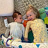 baby, child, play_mat, onesie, toy, carpet, floor, infant, smile, lying_down, cute, indoor, happy, toddler, foot, blanket, colorful, patterned, face, person