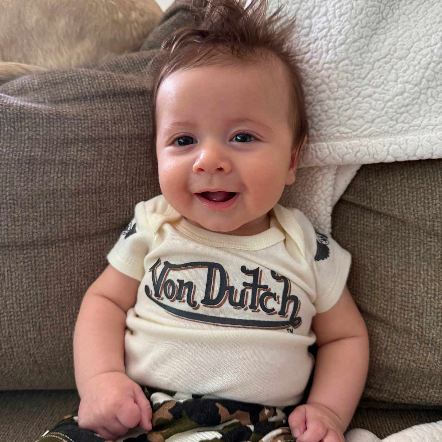 Cosmo joined the competition — help win amazing prizes! baby, smiling, couch, clothing, camouflage, cute, happy, child, indoor, toddler, portrait, sitting, shorts, hair, face, apparel, infant, person, home, relaxed