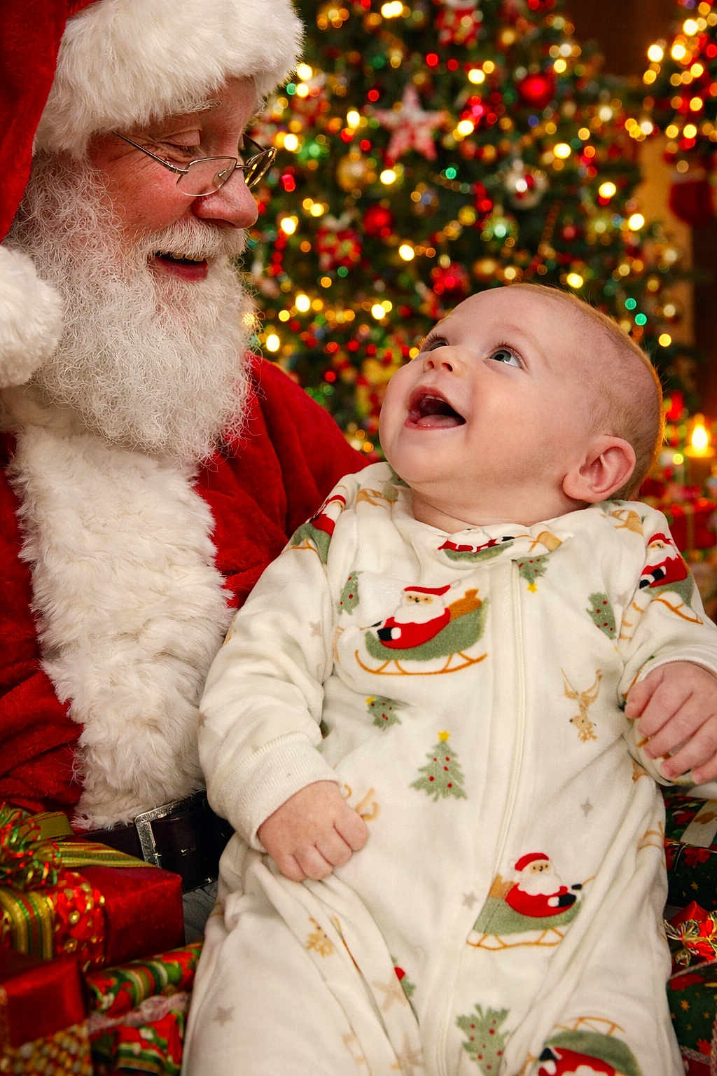 Christian joined the competition — help win amazing prizes! baby, santa_claus, christmas_tree, pajamas, holiday, presents, smiling, festive, celebration, indoor, decorations, beard, glasses, joy, child, red_clothing, christmas_lights, portrait, seasonal, happy