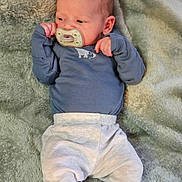 Christian joined the competition — help win amazing prizes! baby, infant, pacifier, clothing, blue_shirt, grey_pants, blanket, soft_texture, lying_down, newborn, cute, small_hands, face, head, skin, indoors, resting, portrait, child, peaceful