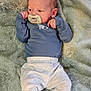 baby, infant, pacifier, clothing, blue_shirt, grey_pants, blanket, soft_texture, lying_down, newborn, cute, small_hands, face, head, skin, indoors, resting, portrait, child, peaceful