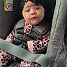 baby, infant, child, car_seat, safety_harness, headband, leopard_print, pink_clothing, onesie, sitting, portrait, face, eyes, expression, indoor, vehicle, automobile, textile, fashion, safe_travel