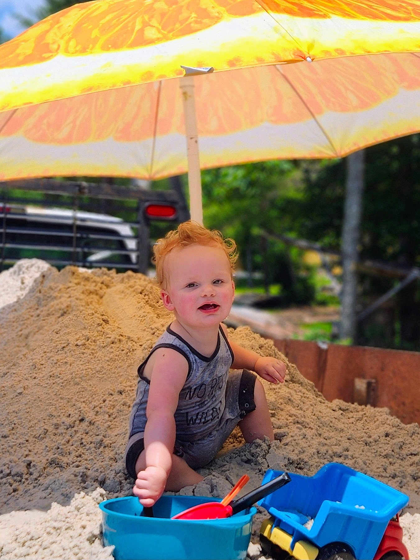 Bobby Ray joined the competition — help win amazing prizes! toddler, child, sand, bucket, shovel, toy_truck, umbrella, outdoor, sunny, play, summer, curly_hair, smiling, fun, blue_bucket, yellow_umbrella, sand_pile, summer_clothes, happy, nature