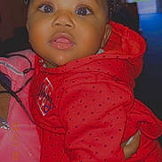 Journei joined the competition — help win amazing prizes! baby, child, curly_hair, red_hoodie, bow, face, eyes, person, portrait, indoor, clothing, hand, pink, warm_lighting, cute, expression, holding, wearing, young, infant