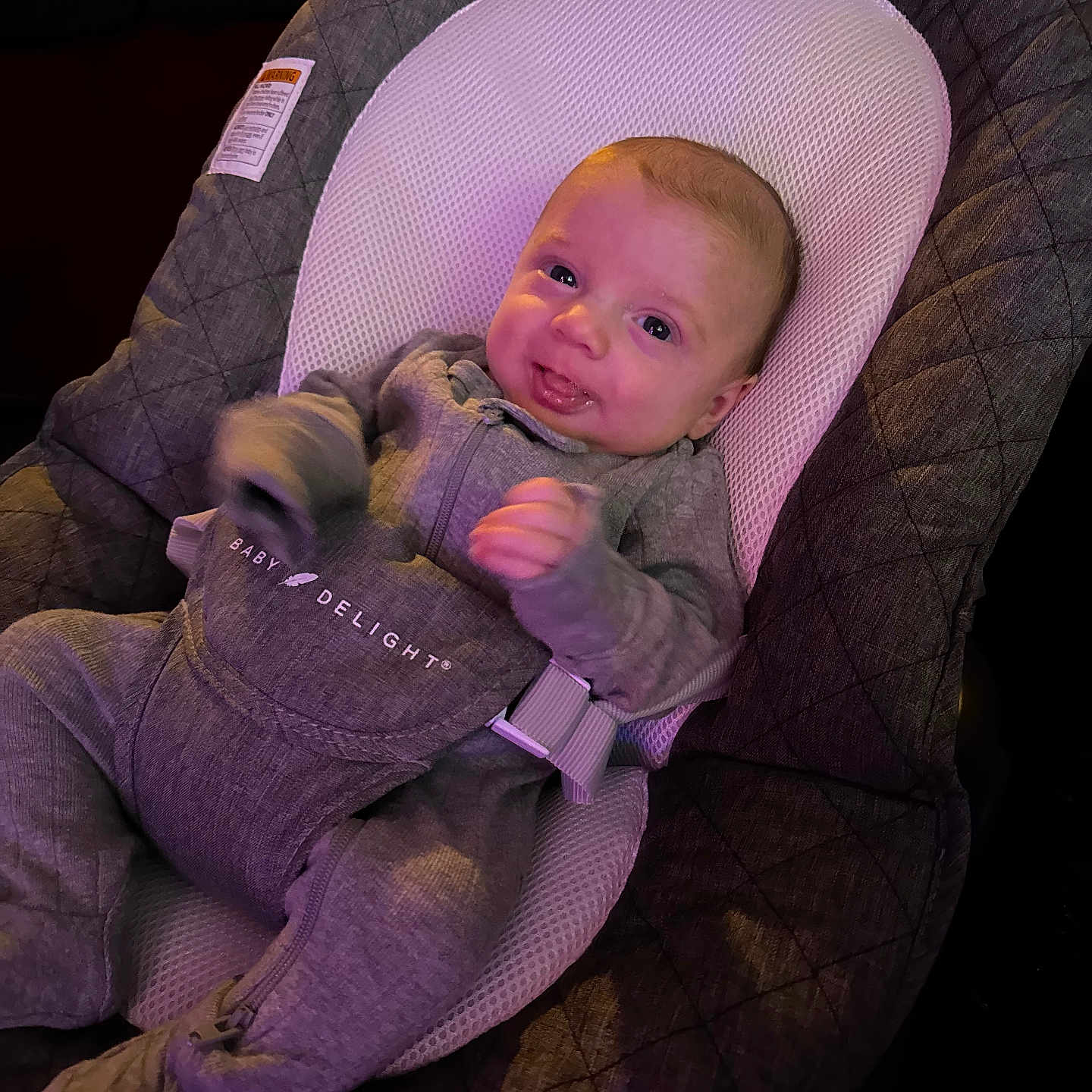 Jackson is registered to the contest to win money with this photo: baby, bodypart, car, car_interior, clothing, couch, face, finger, furniture, hand, hat, head, knitwear, pants, person, photography, portrait, sweater, transportation, vehicle