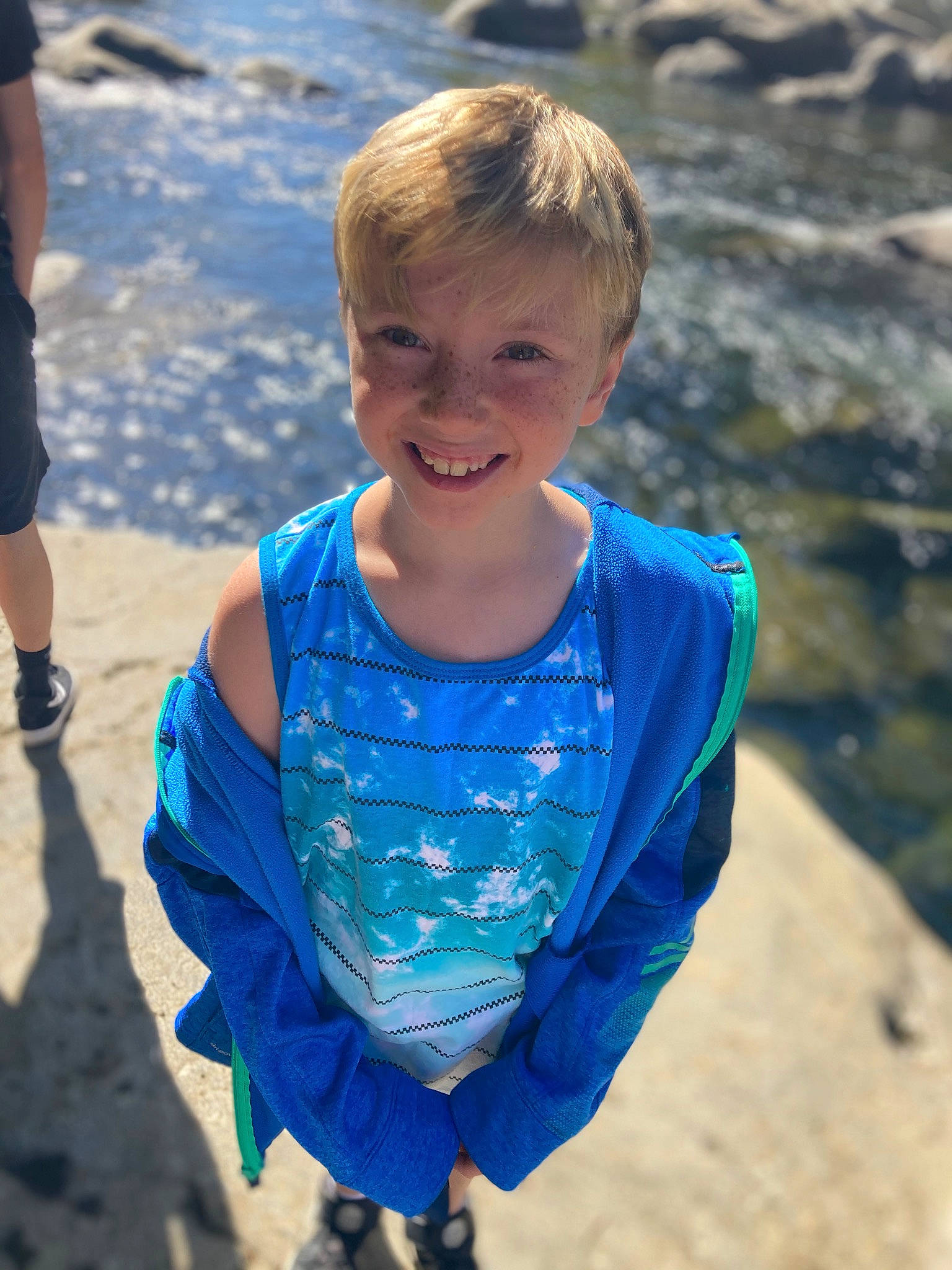 Milo is registered to the contest to win money with this photo: azure, body_of_water, cool, daytime, eye, fun, grass, hand, happy, human_body, joy, leisure, mammal, people_in_nature, person, sand, smile, standing, travel, tree