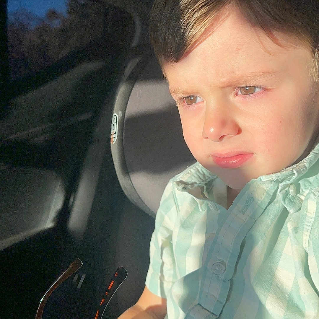Leonel is registered to the contest to win money with this photo: boy, car_interior, car_seat, casual_clothing, child, daylight, face, holding, indoors, light_and_shadow, person, portrait, seat, seatbelt, serious_expression, short_hair, sunglasses, sunlight, window, young