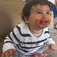 Maé participe au concours pour gagner de l'argent avec cette photo : toddler, child, chocolate, messy_face, sweater, striped_clothing, sitting, couch, curly_hair, barefoot, indoors, cute, happy, playful, young_child, smiling, stained_clothing, portrait, baby, hands