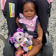 Azaria joined the competition — help win amazing prizes! toddler, child, car_seat, pink_clothing, plush_toy, smiling, hair_pigtails, footwear, outdoor, asphalt, seatbelt, baby, toy, cute, happy, person, infant, sitting, accessory, clothing
