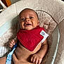 baby, infant, smiling, red_bib, knit_outfit, baby_chair, cushion, indoor, happy, person, child, seat, cute, clothing, hand, face, portrait, comfort, young, relaxed