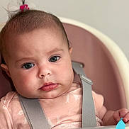 Luna joined the competition — help win amazing prizes! baby, child, face, high_chair, pink_bow, hair, serious_expression, blue_eyes, infant, straps, toy, colorful, closeup, seated, indoor, skin, clothing, person, head, cute