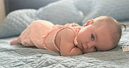 Luna is registered to the contest to win money with this photo: baby, infant, bed, blanket, quilt, sleepwear, pink_clothing, head, face, skin, eyes, earrings, resting, lying_down, indoor, soft_light, peaceful, portrait, cute, child