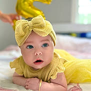 Luna joined the competition — help win amazing prizes! baby, child, yellow_clothing, headband, bow, bracelet, balloon, number_5, blanket, indoor, portrait, cute, infant, celebration, smiling, face, eyes, skin, hand, lying_down
