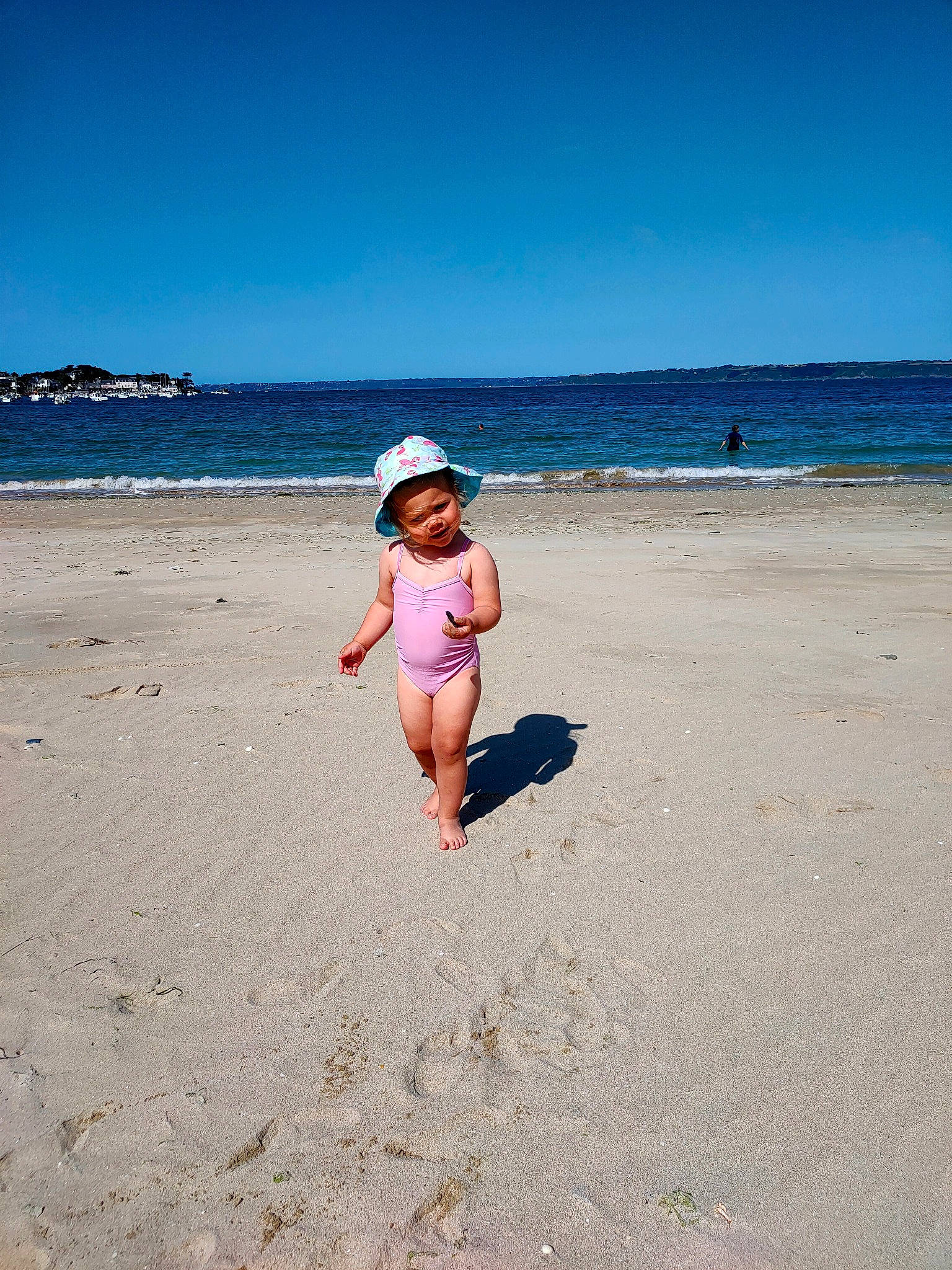 Yaëlle a rejoint le concours — aidez-le/la à gagner de superbes lots ! azure, beach, coastal_and_oceanic_landforms, fun, happy, hat, holiday, horizon, landscape, leisure, morning, people_in_nature, people_on_beach, person, recreation, sky, sunlight, toddler, tree, water