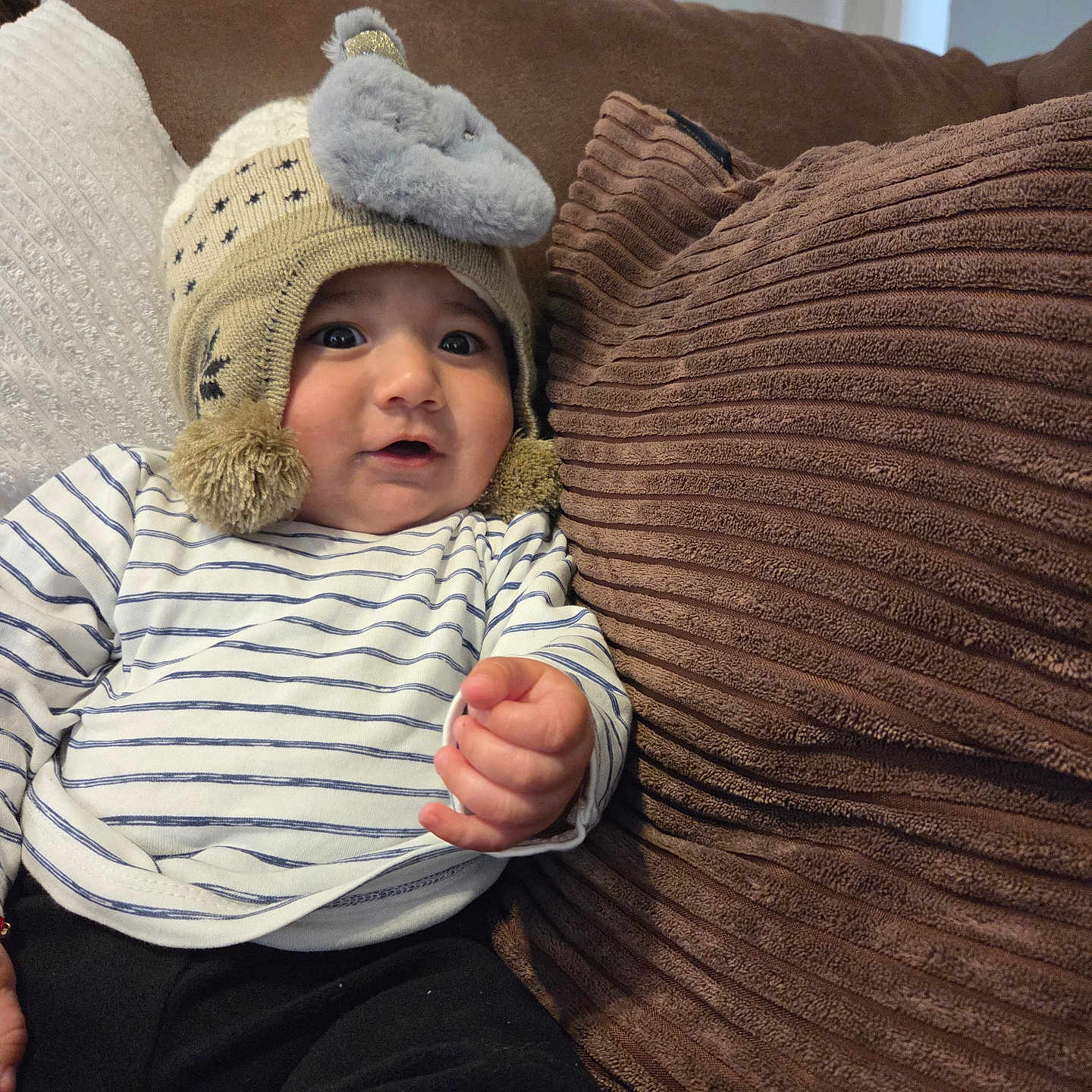 Enzo joined the competition — help win amazing prizes! baby, brown_pillow, casual_clothing, child, couch, cozy, curious, elephant, hand, hat, indoor, infant, knitted_hat, person, pillow, plush, smiling, soft, striped_shirt, white_pillow