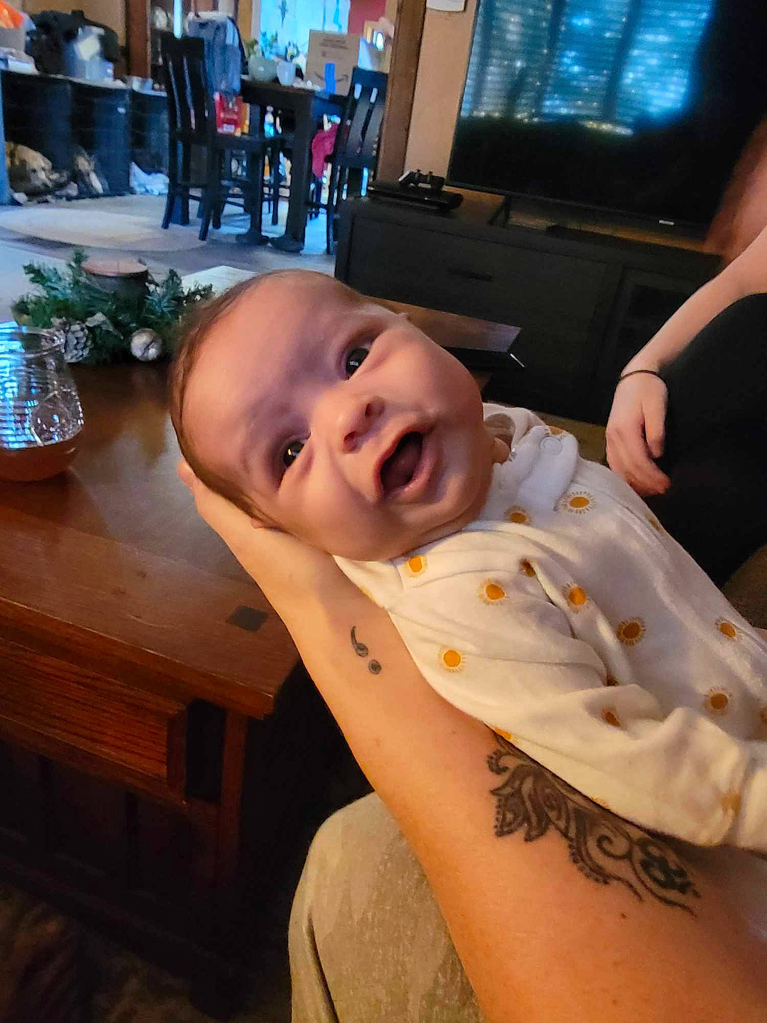 Alayna is registered to the contest to win money with this photo: abdomen, baby, baby_toddler_clothing, chest, child, comfort, elbow, event, flooring, fun, happy, human_leg, mouth, person, picture_frame, room, sitting, smile, television, thumb