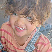Harley is registered to the contest to win money with this photo: child, smiling, face, hair, denim_overalls, striped_shirt, indoor, table, chair, happy, cute, portrait, young, person, clothing, casual, toddler, eyes, expression, playful