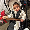 baby, child, stroller, portrait, indoors, seated, serious_expression, brown_hair, striped_clothing, socks, harness, safety_bar, chair, shopping, retail_store, floor, table, furniture, infant, face