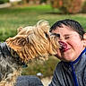 Bruno is registered to the contest to win money with this photo: blurred_background, close_up, dog, eyes_closed, face, garden, grass, jacket, joy, kiss, licking, long_hair, outdoor, park, person, pet, portrait, puppy, shaggy_fur, smiling