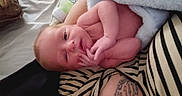 Owen joined the competition — help win amazing prizes! newborn, baby, infant, blanket, striped_shirt, tattoo, bottle, bed, hand, face, skin, person, lying_down, soft_texture, curious, indoors, closeup, human, resting, cute