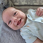 Magnus is registered to the contest to win money with this photo: baby, child, clothing, comfort, cute, elephant_toy, face, hand, happy, indoors, infant, lying_down, playful, plush_toy, portrait, smiling, soft, texture, towel, young