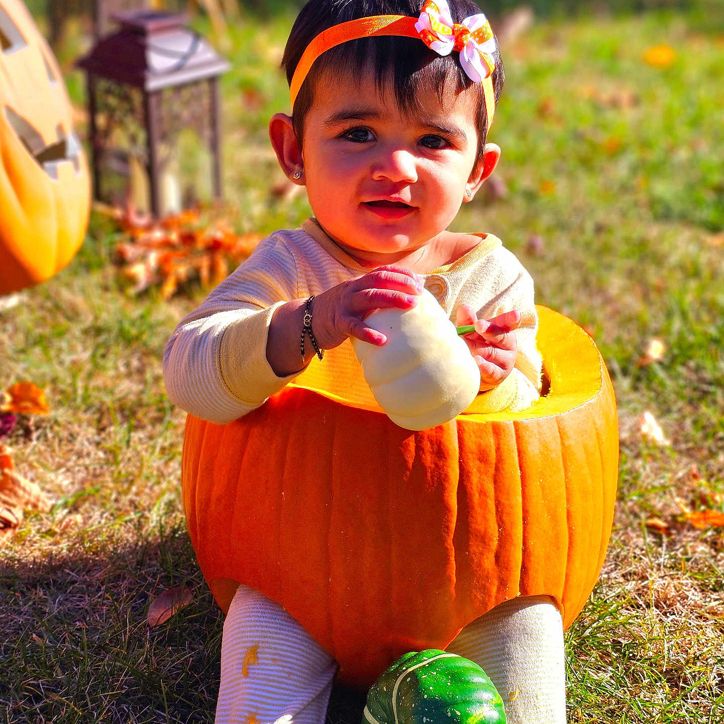 Aashvi is registered to the contest to win money with this photo: baby, bodypart, clothing, face, finger, food, fruit, grass, hand, head, lawn, person, photography, plant, portrait, produce, pumpkin, sphere, squash, vegetable