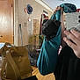 Oso joined the competition — help win amazing prizes! puppy, black_dog, teal_sling, mirror_selfie, person, hand, yellow_bag, door, hat, wall_decor, dog_crate, wooden_floor, indoor, living_room, plant, reflection, phone, casual, clothing, furniture