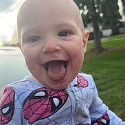 Easton is registered to the contest to win money with this photo: baby, child, tongue_out, smiling, spiderman, clothing, outdoor, grass, tree, person, cute, happy, playful, portrait, infant, hand, nature, daylight, jumpsuit, fun