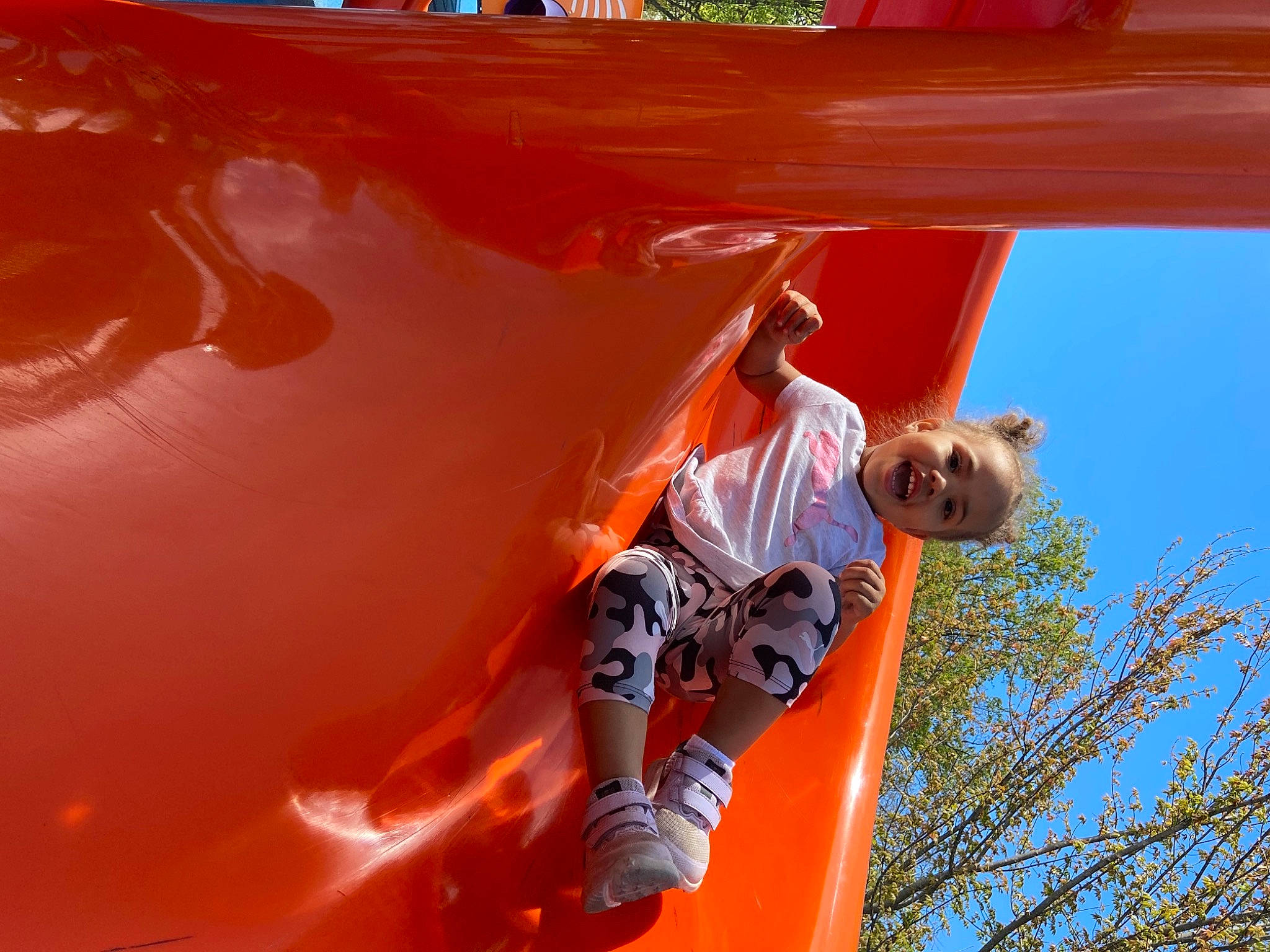 Paityn is registered to the contest to win money with this photo: adventure, automotive_exterior, child, chute, city, extreme_sport, fun, hood, leisure, motor_vehicle, orange, outdoor_play_equipment, person, playground, playground_slide, recreation, red, sky, t_shirt, tree