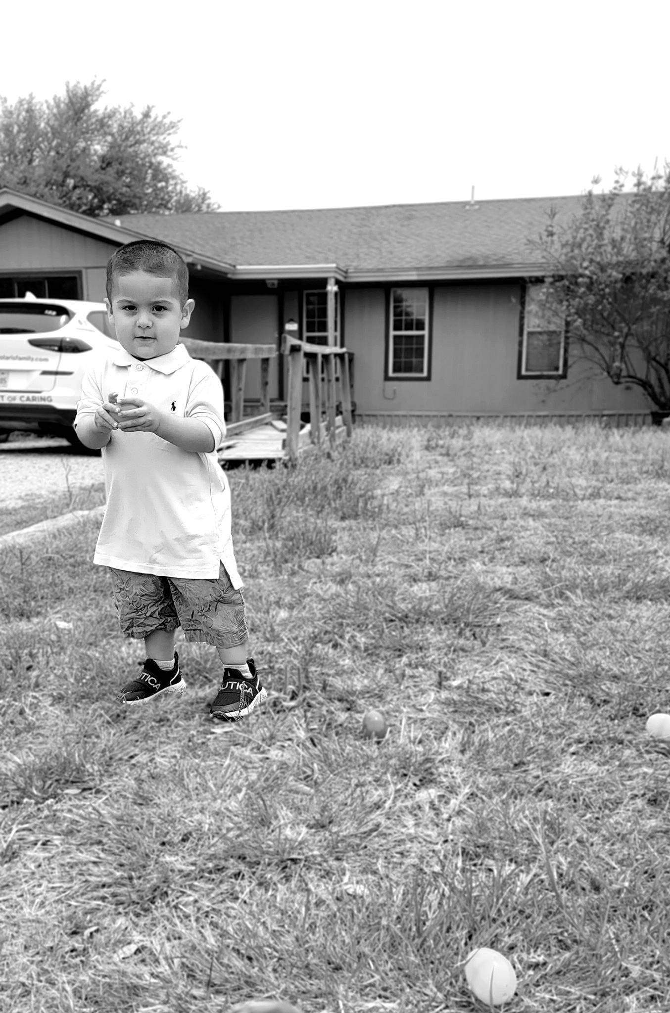 Slade is registered to the contest to win money with this photo: ball, black, black_and_white, building, football, gesture, grass, happy, house, leg, people_in_nature, person, plant, rural_area, shorts, sky, style, toddler, tree, white