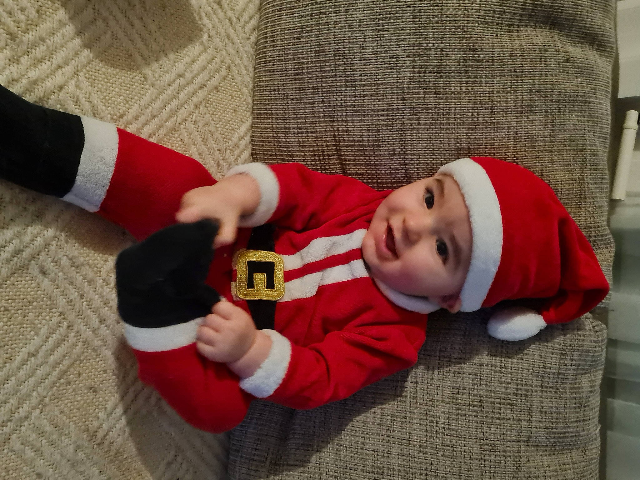 Theo participe au concours pour gagner de l'argent avec cette photo : baby, baby_toddler_clothing, cap, carmine, child, christmas, christmas_eve, comfort, fictional_character, flooring, fun, headgear, headwear, holiday, lap, person, room, santa_claus, sleeve, smile