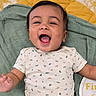 baby, smiling, infant, onesie, blanket, happy, face, child, laying, cute, pattern, mouth_open, celebration, milestone, skin, arm, indoor, young_child, joy, expression