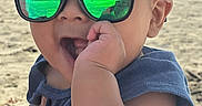 Adrian is registered to the contest to win money with this photo: baby, child, beach, sunglasses, blue_sky, ocean, sand, outdoor, portrait, sitting, smiling, infant, fashion, reflective_lenses, sunlight, shoreline, summer, hand, clothing, family