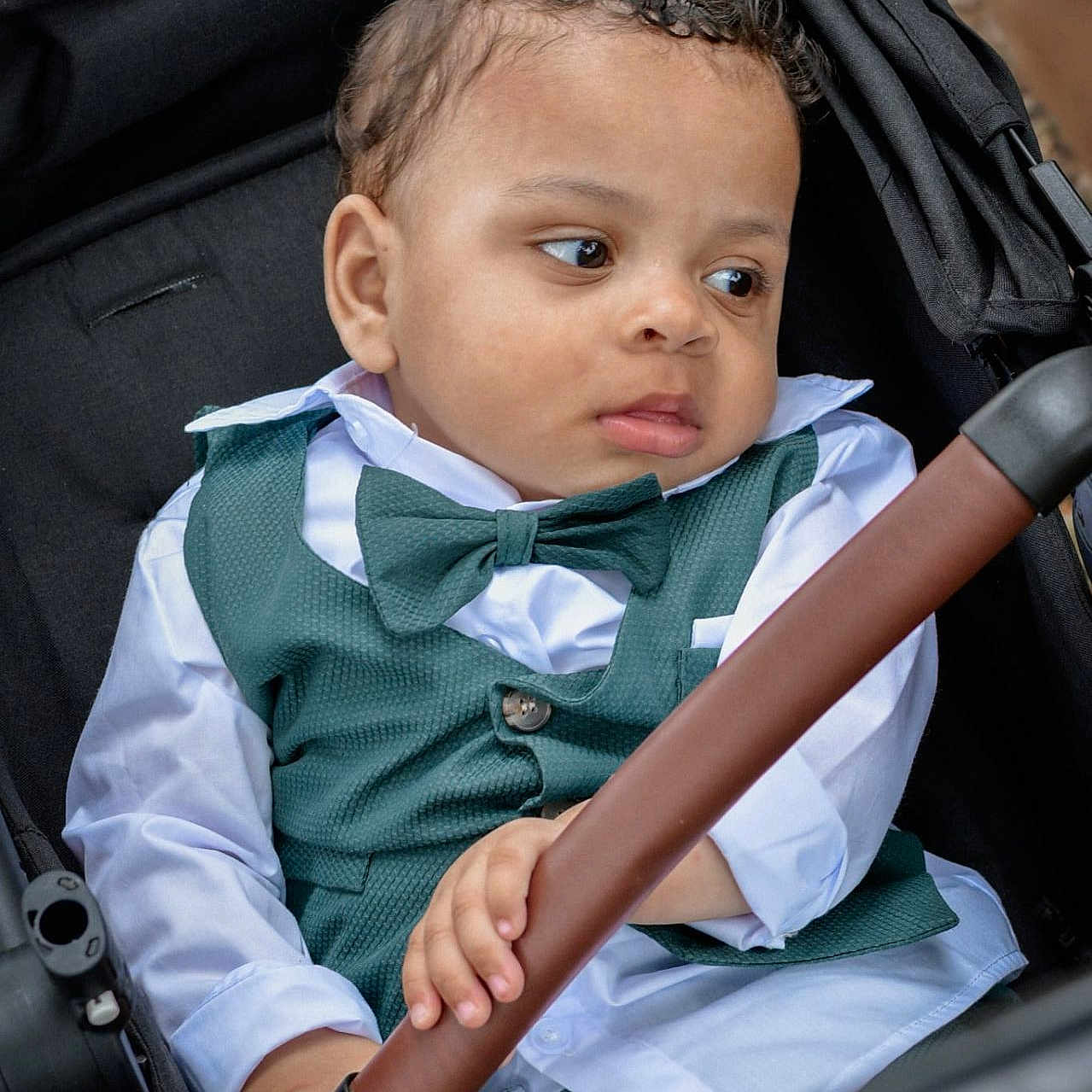 Nunzio a rejoint le concours — aidez-le/la à gagner de superbes lots ! baby, bow_tie, casual, child, clothing, curly_hair, cute, expression, face, green_vest, grip, hand, outdoor, person, portrait, seat, stroller, toddler, white_shirt, young_child