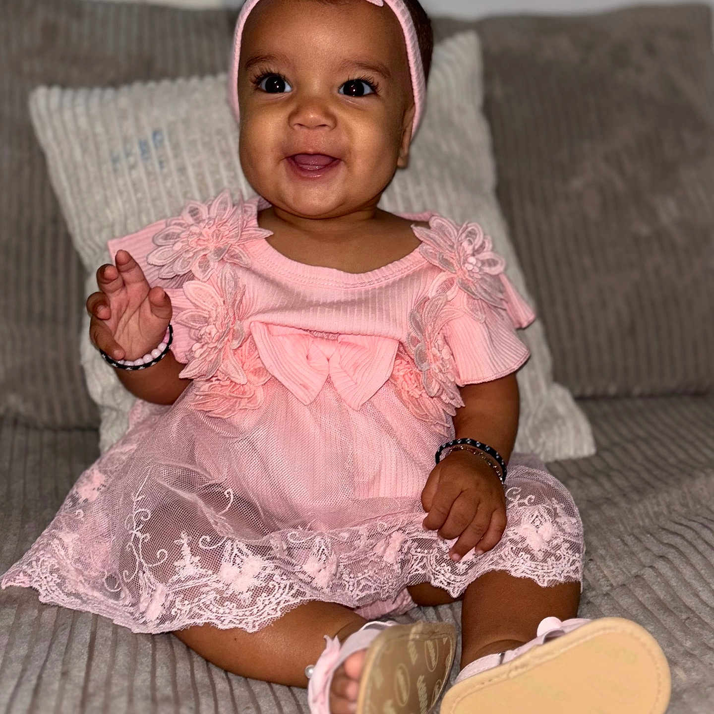 Keliyah a rejoint le concours — aidez-le/la à gagner de superbes lots ! apparel, baby, bracelet, child, couch, cozy, cute, female, footwear, happy, headband, indoors, infant, lace, person, pink_dress, portrait, sitting, smiling, young_child