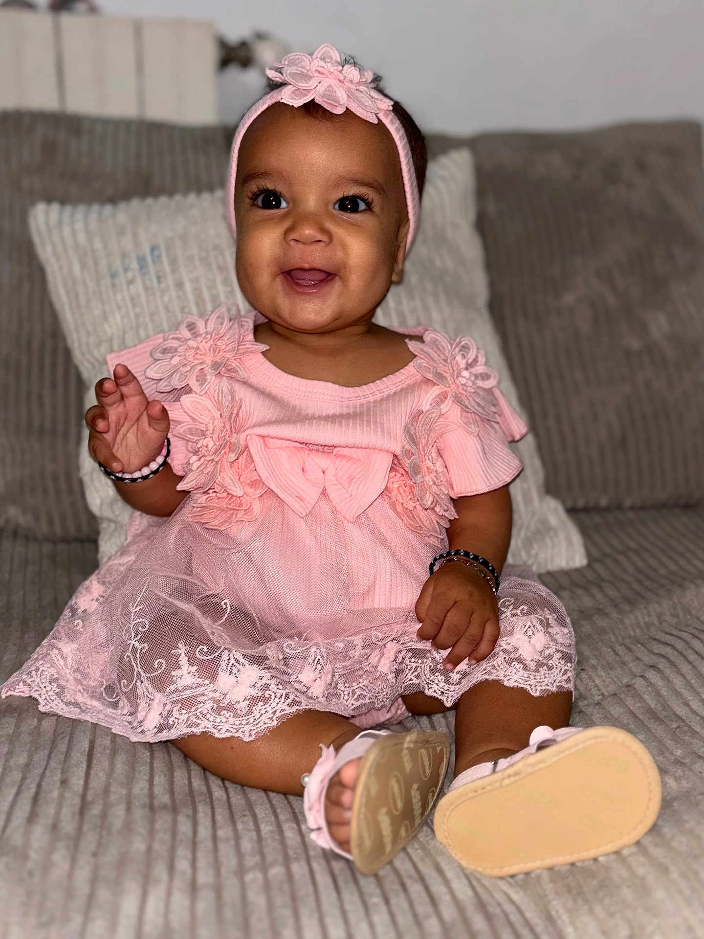 Keliyah a rejoint le concours — aidez-le/la à gagner de superbes lots ! baby, child, smiling, pink_dress, headband, sitting, indoors, couch, happy, cute, footwear, bracelet, lace, portrait, infant, young_child, female, apparel, person, cozy