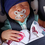 Ashua is registered to the contest to win money with this photo: baby, blanket, car_seat, child, clothing, comfort, cute, footprints, hand, hat, headwear, indoors, infant, pacifier, pattern, peaceful, portrait, resting, safety_belt, sleeping