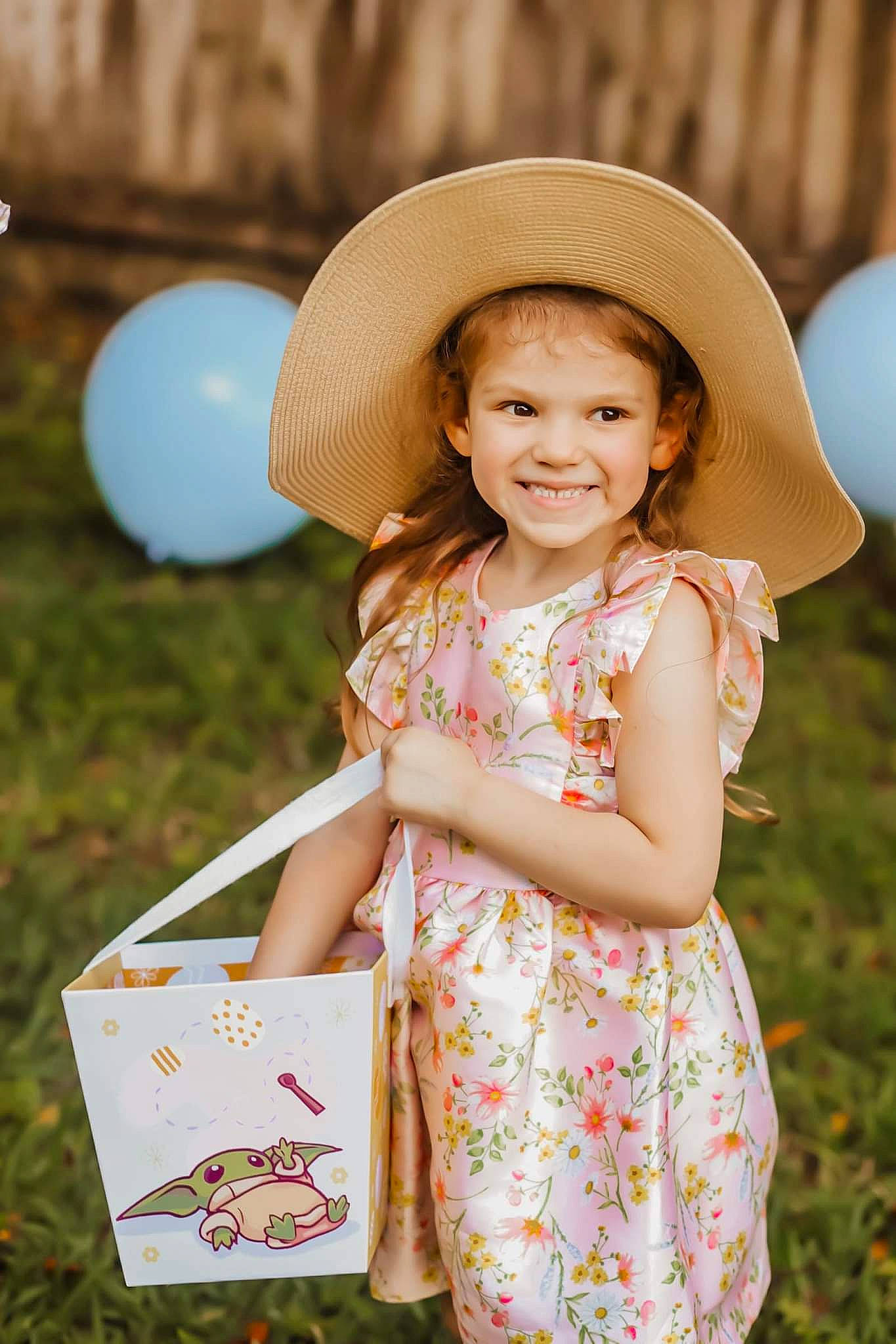 Mallory is registered to the contest to win money with this photo: balloon, beauty, child, dress, event, fun, grass, happy, hat, headgear, headwear, joy, leisure, pattern, people_in_nature, person, sitting, skin, smile, summer