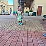 toddler, child, girl, dress, shoes, outdoor, walking, brick_path, pillars, people, daylight, smile, curly_hair, building, architecture, lanterns, plants, benches, happy, urban