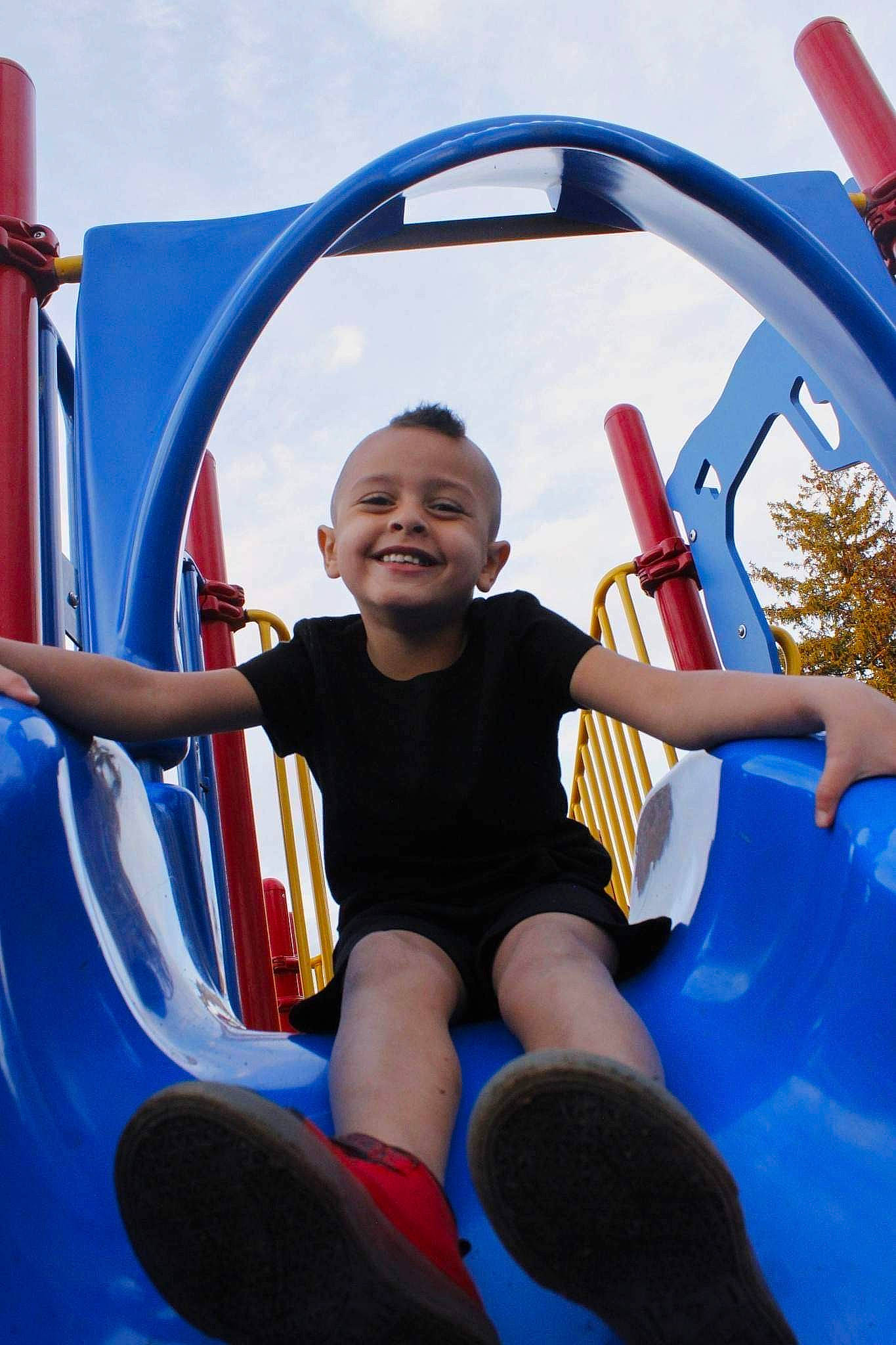 Zamari is registered to the contest to win money with this photo: blue, chute, cloud, fun, happy, joy, leisure, light, organ, outdoor_play_equipment, outdoor_recreation, person, photograph, playground, recreation, red, shorts, sky, smile, toddler