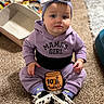 baby, girl, child, purple_outfit, headband, bow, sitting, carpet, indoor, toys, storage_bin, curious, pout, shoes, socks, hoodie, floor, playtime, portrait, cute
