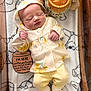 newborn, baby, sleeping, hoodie, yellow_pants, blanket, plush_toy, soft_toys, wooden_sign, birth_details, cozy, infant, cute, peaceful, indoors, portrait, baby_clothes, small_hands, baby_feet, resting